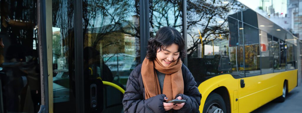 Jovem utilizando smartphone no ponto de ônibus